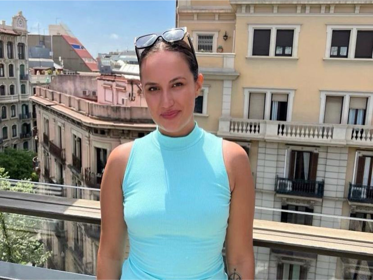 picture of a female CLOUD NINE employee in a light blue top standing on a rooftop with buildings in the background